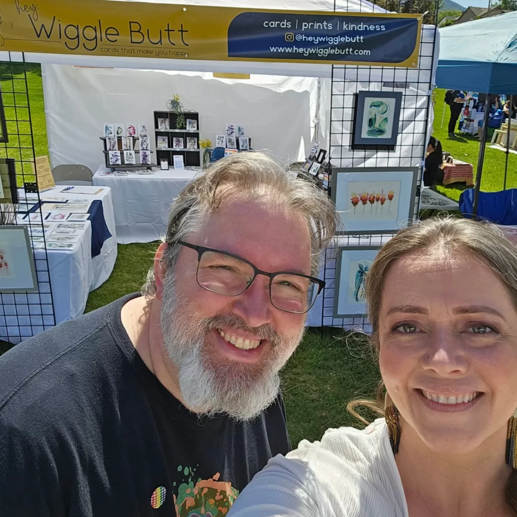 picture of Angela and Rich standing in front of their booth at the yART Sale, their first art show.